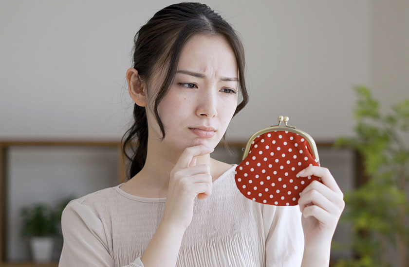 財布を持って悩んでいる女性
