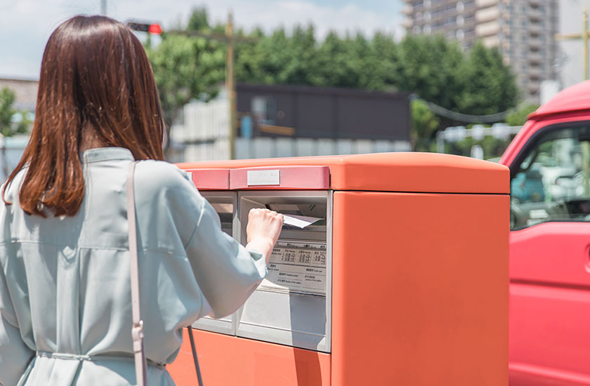 内容証明書をポストに投函する既婚女性
