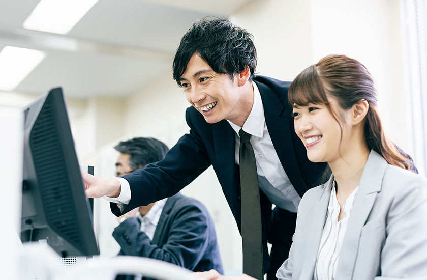 職場の後輩女性と話をする夫