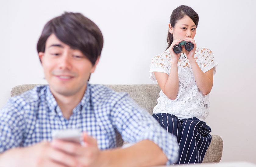 スマホを見ているパートナーを監視する女性
