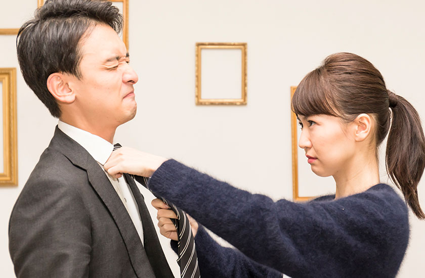 夫のネクタイをきつく絞める既婚女性