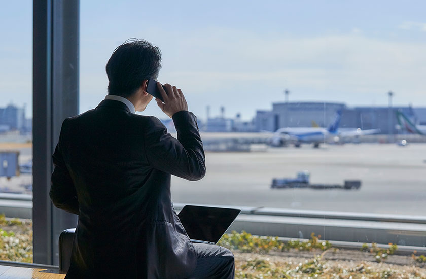 出張先の空港から電話をする既婚男性