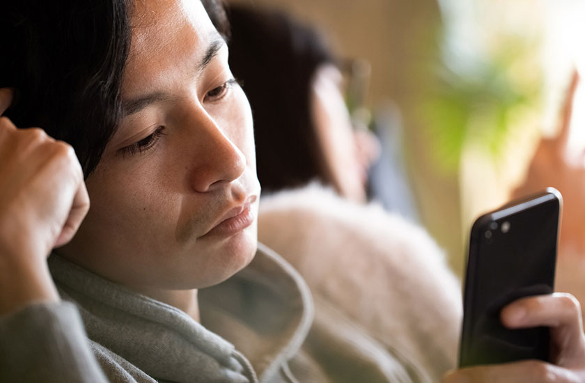 不倫相手とスマホで連絡を取り合う既婚男性