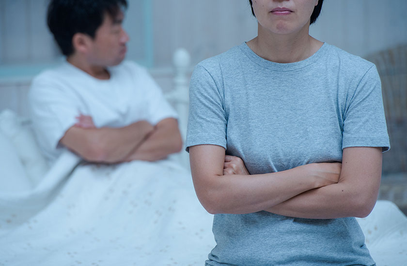 寝室で腕組みをする夫婦